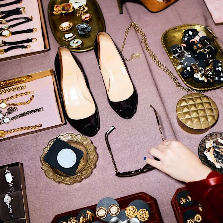 A table at the Manhattan Vintage Show 2025 displaying vintage accessories, including black patent leather shoes, watches, jewelry, and sunglasses.