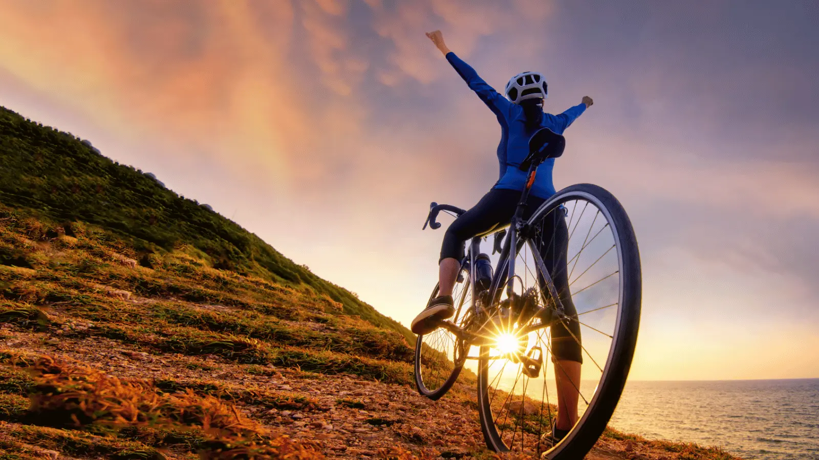 Cyclist celebrating at sunset on a scenic hill for sports marketing examples of inspiration and achievement.